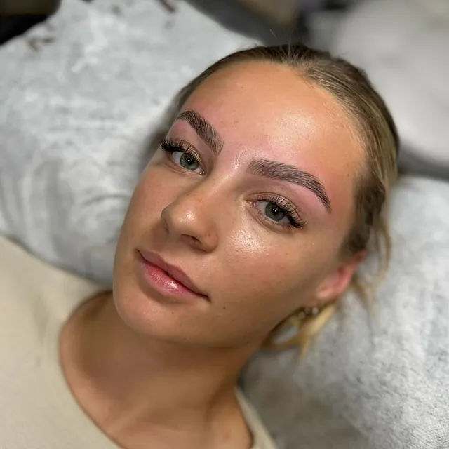 Kvinne med definerte bryn og lange vippe-extensions, ligger på benk.