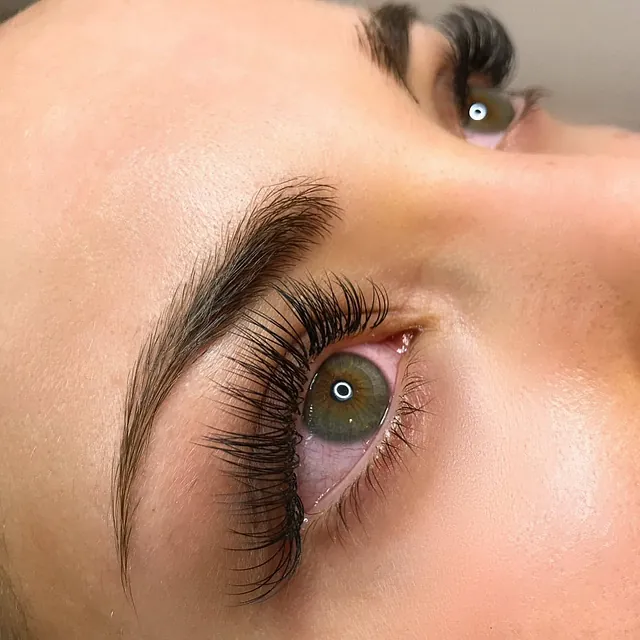 Nærbilde av øye med fyldige vippe-extensions og definerte bryn.