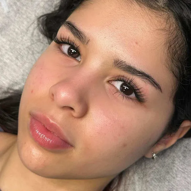 Kvinne med mørkt hår og naturlig hud, med påsatte vippe-extensions.