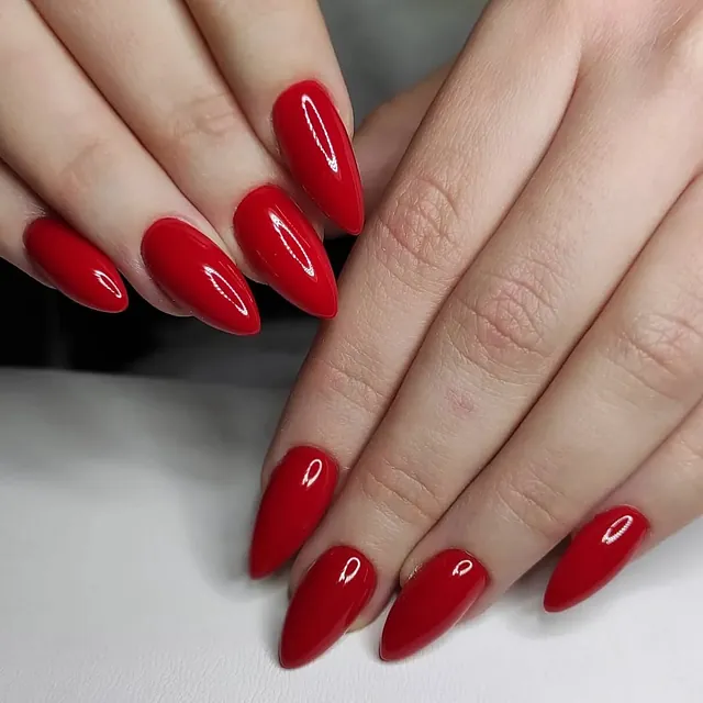 Negler med glansfull rød lakk i spiss, mandelformet stil.