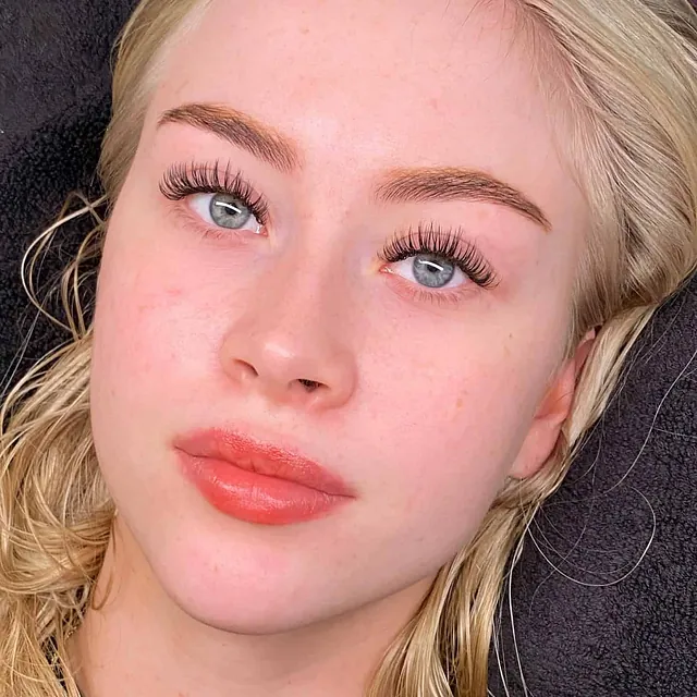 Kvinne med lyseblå øyne og voluminøse vipper etter behandling.