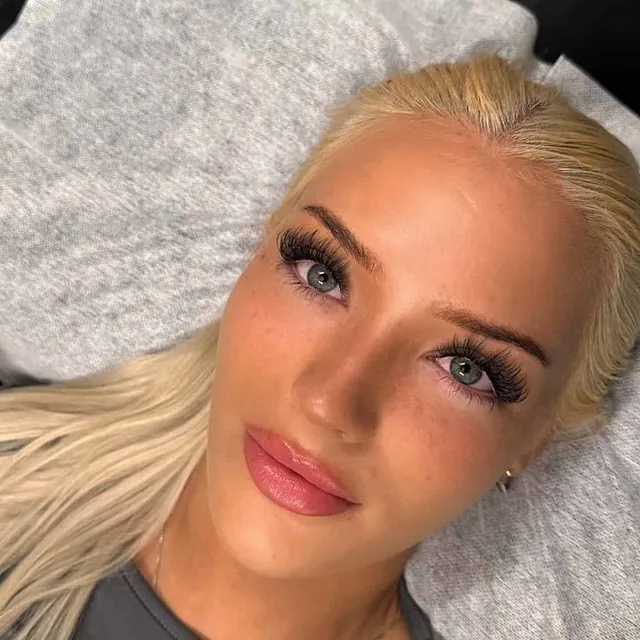 Kvinne med langt lyst hår og dramatiske vipper etter vippesett.